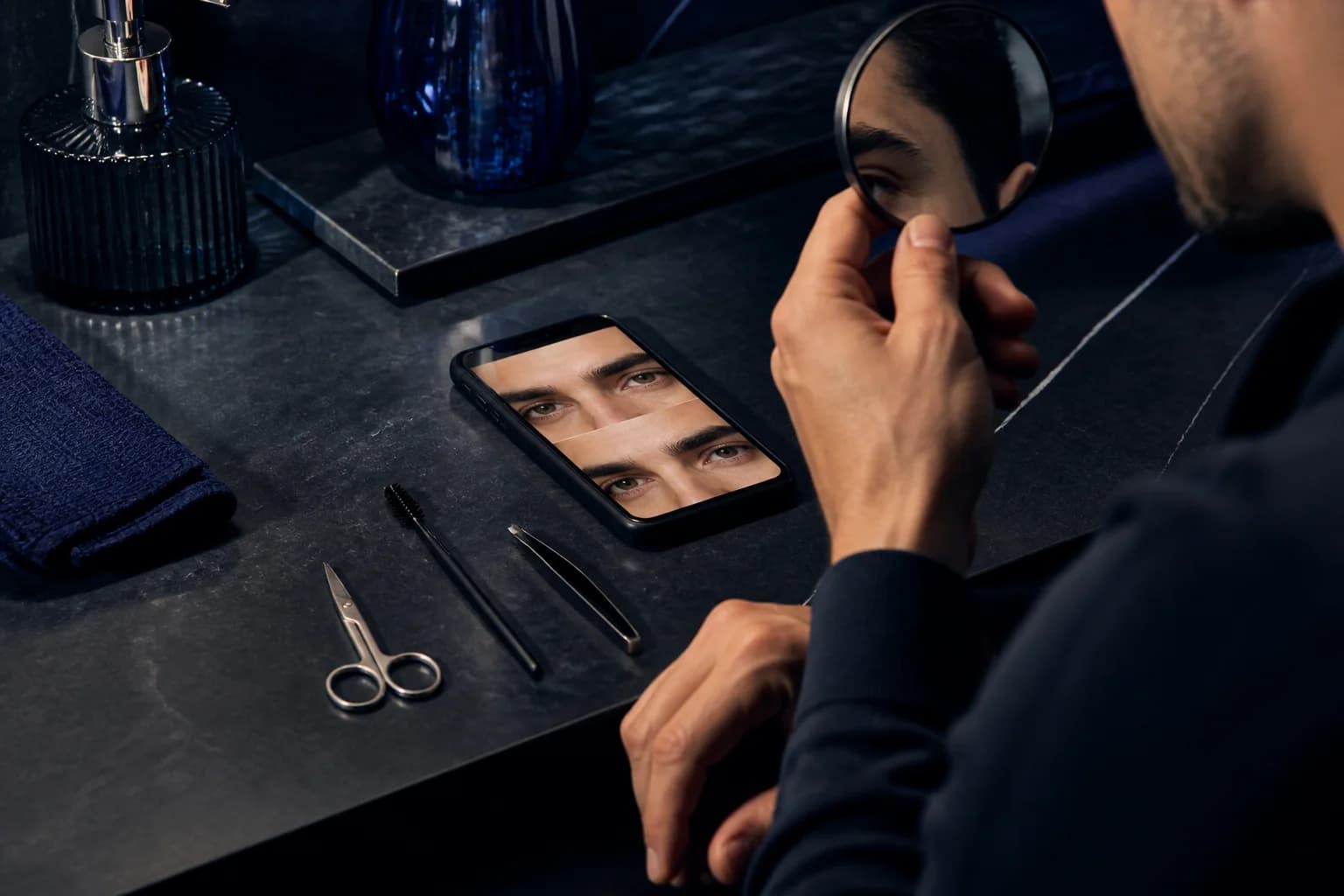 Man planning eyebrow grooming with a mirror, spoolie, scissors, tweezers and a before-and-after preview